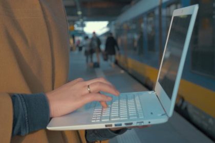 Une personne utilise son ordinateur devant un train de la RATP